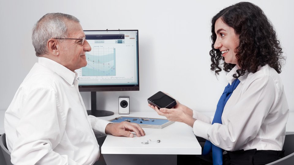 Hearing aid dispenser shows new hearing aids to a customer