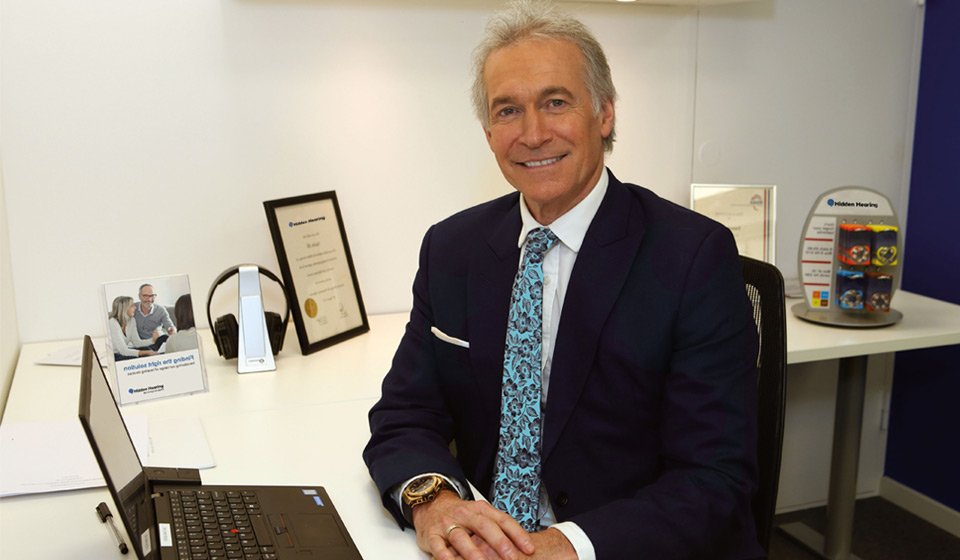 Image shows Dr Hilary Jones at a desk in a Hidden Hearing branch