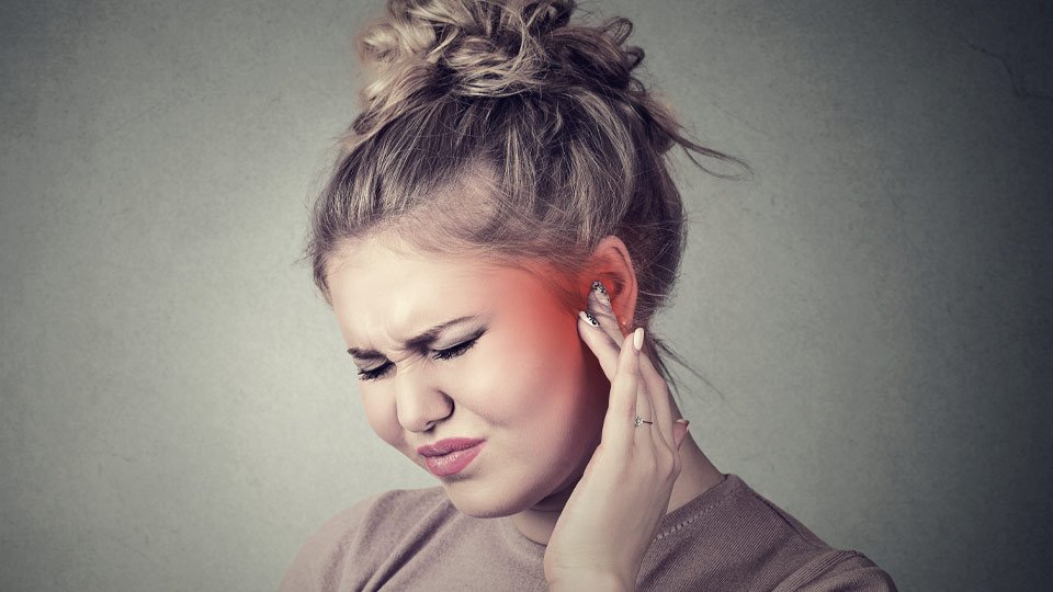 Image shows a girl touching her ear as she is in pain because of an outer ear infection