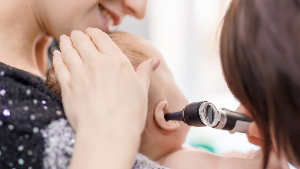 Image shows a baby getting ear checked