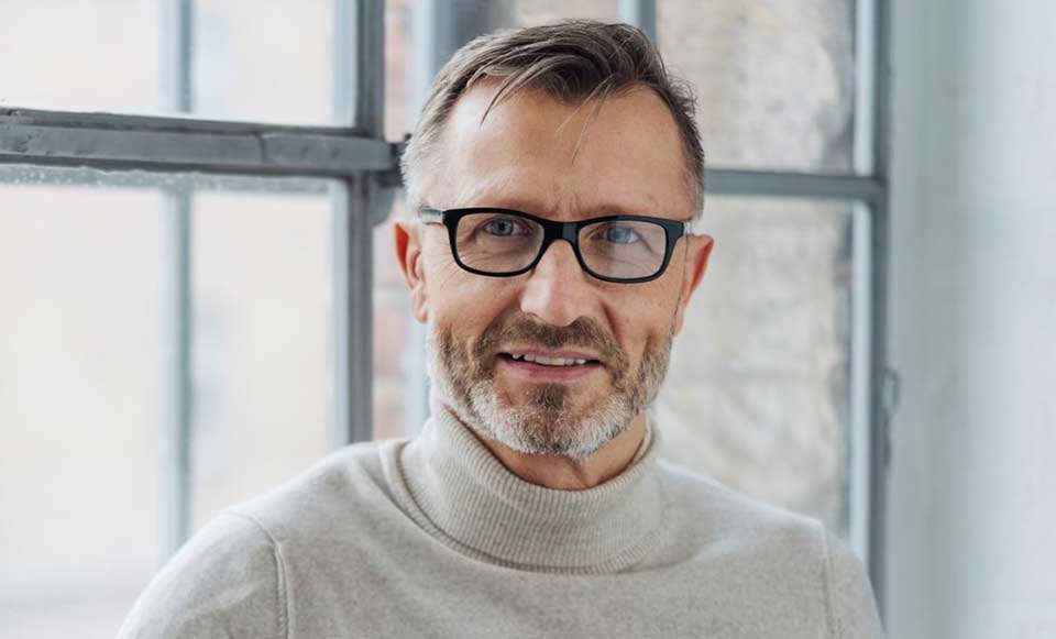Image shows man wearing spectacle hearing aids