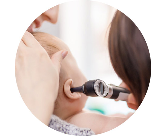 Image shows an audiologist looking in a baby's ear