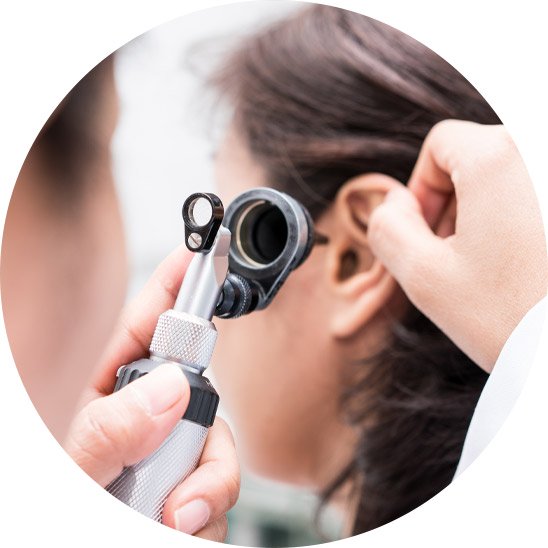 Image shows an audiologist using an otoscope to look into a patient's ear