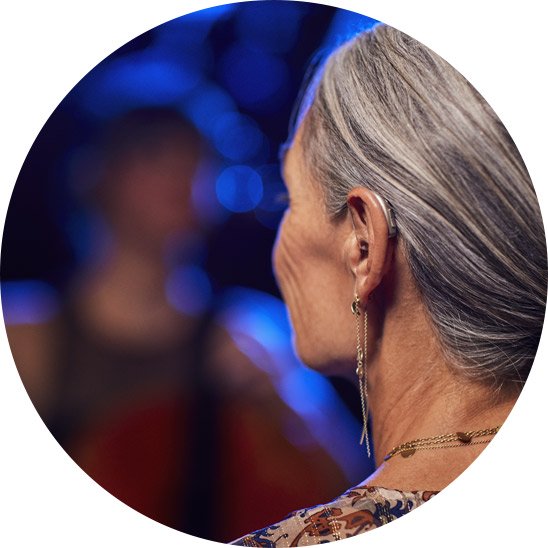 Image shows a woman wearing a digital hearing aid to help with her bilateral hearing loss
