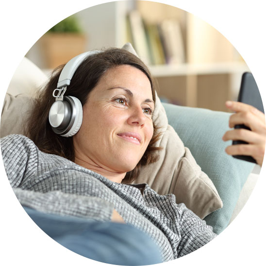 Image shows a woman listening to music on her smartphone through headphones