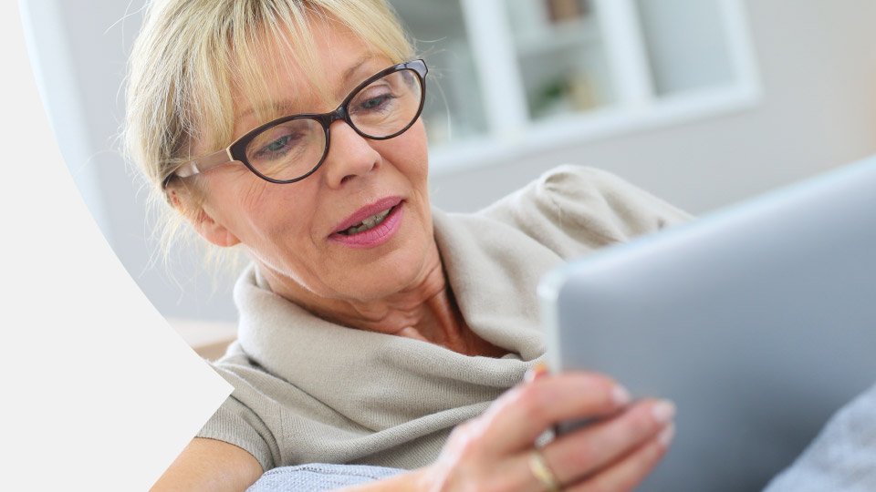 imagem mostra mulher sorridente a olhar para um tablet