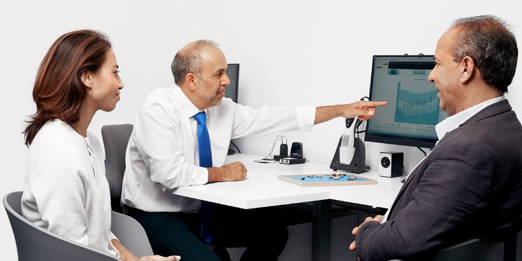 image shows people and audiologist looking at a screen