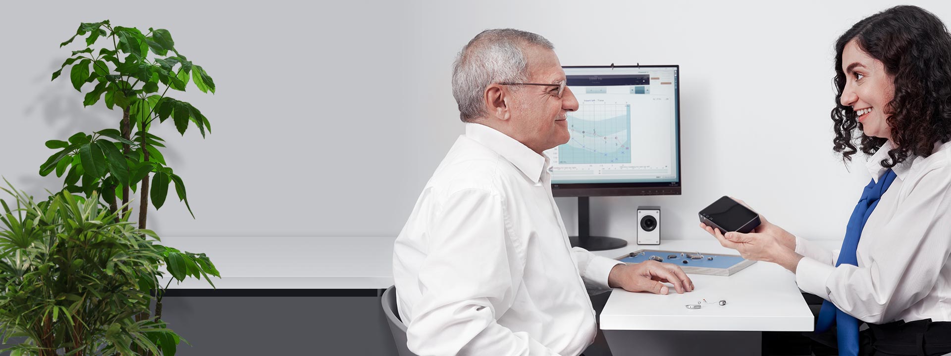 Billede viser en mand med en hørespecialist, der ser på tilbehør til høreapparater 