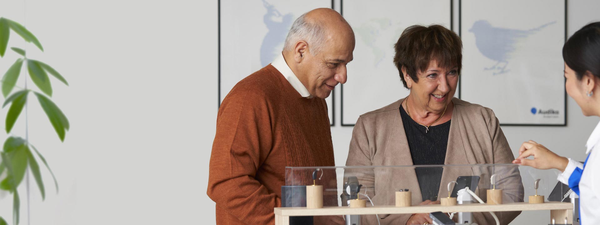 La imagen muestra una pareja con un audioprotesista mirando audífonos 