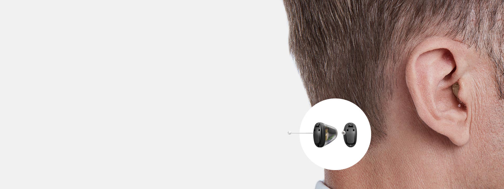 La imagen muestra un audífono intrauricular en el oído de un hombre