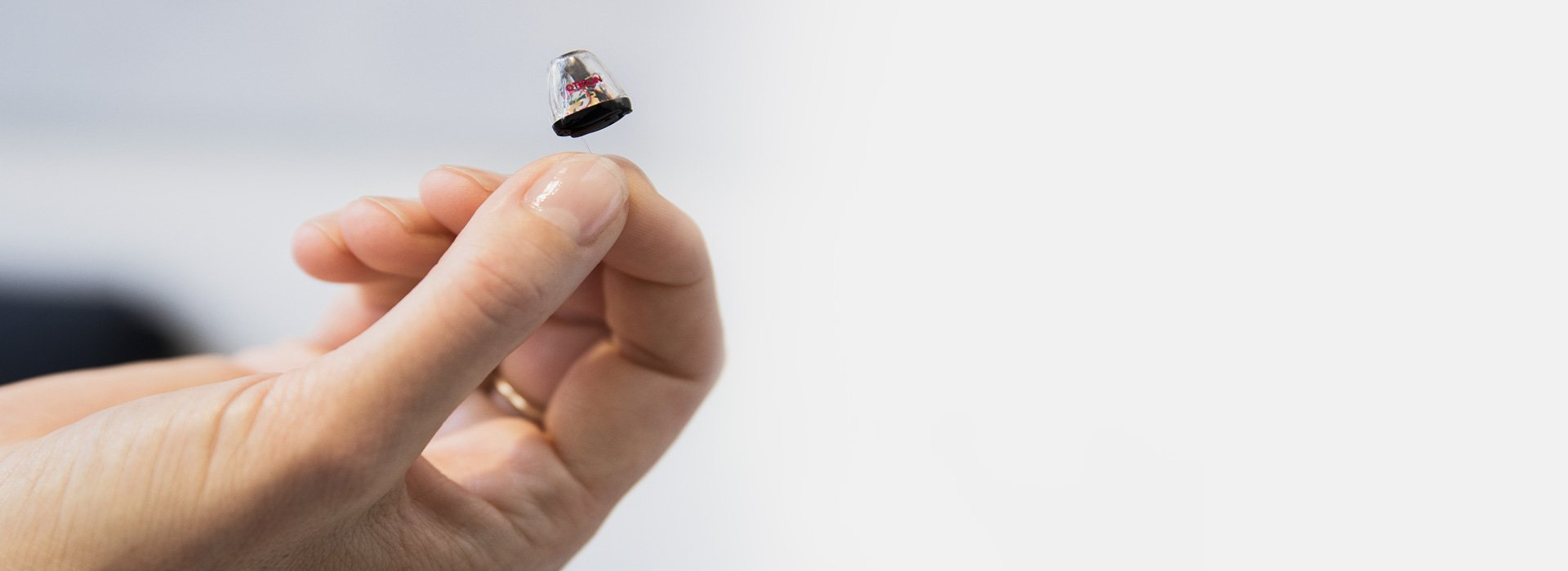 Image shows hand holding a hearing aid