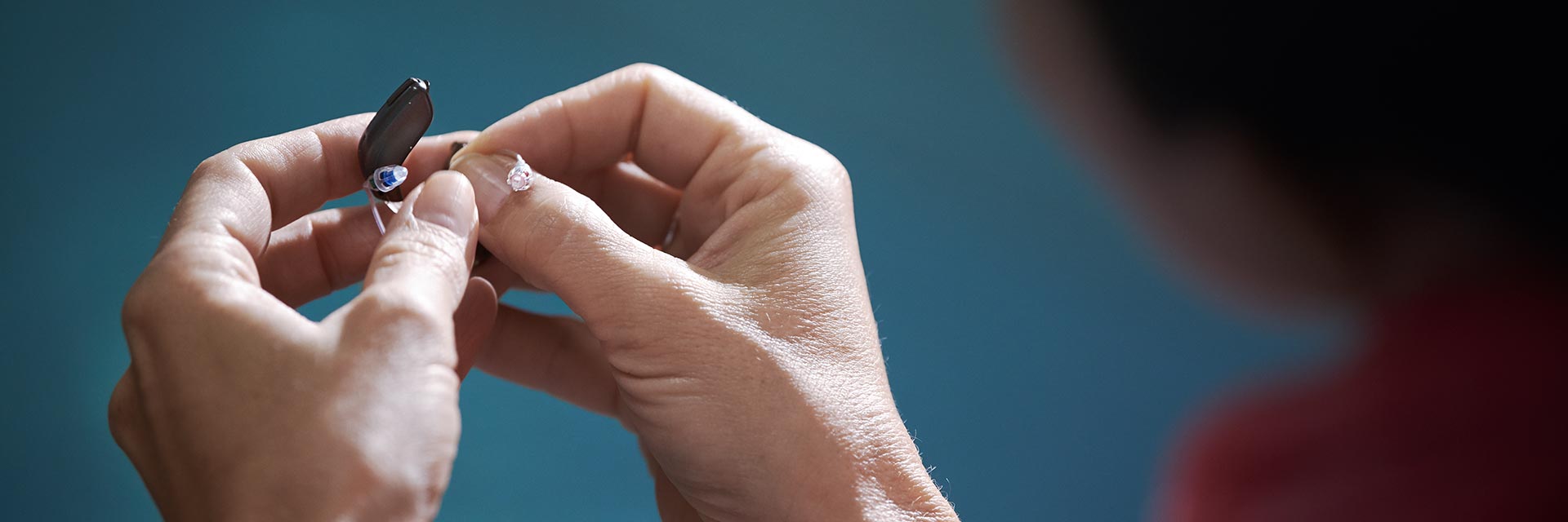 Afbeelding van twee handen die gehoorapparaatbatterijen uitwisselen