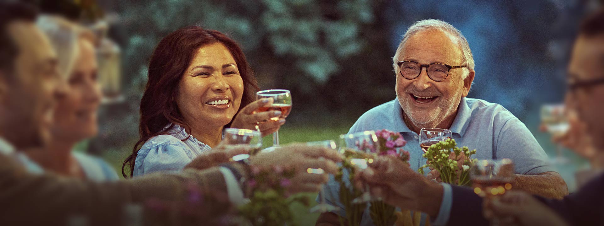 La imagen muestra un hombre feliz con otras personas en una cena