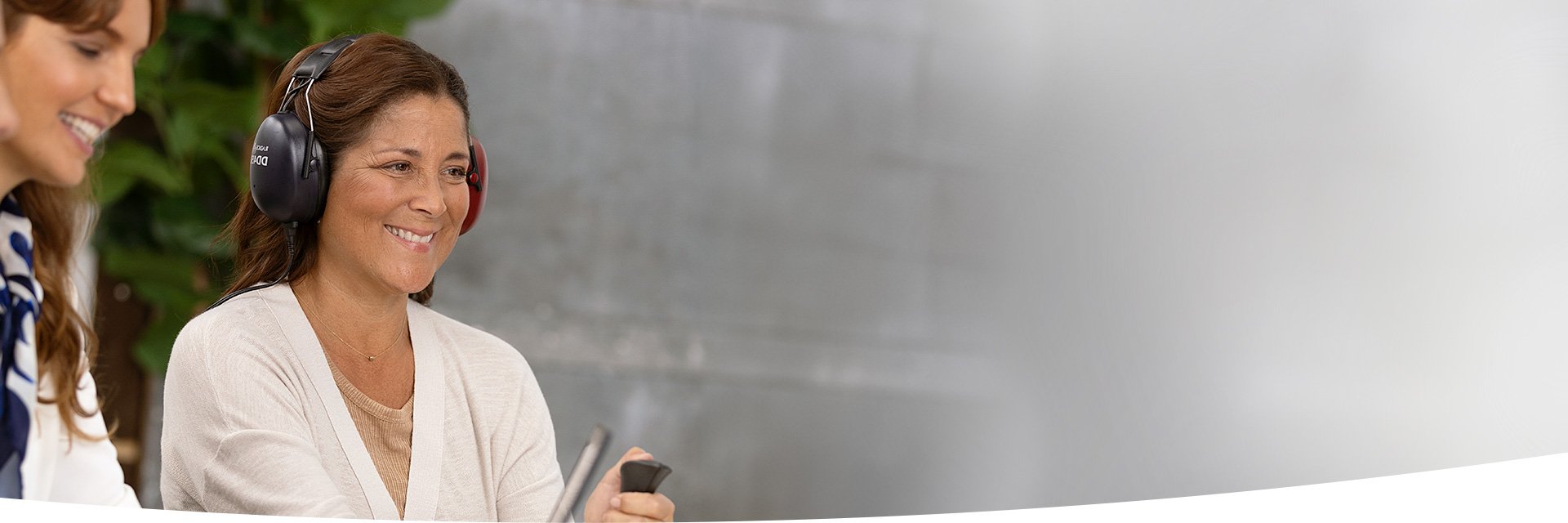 Image shows woman with headphone taking the online hearing test