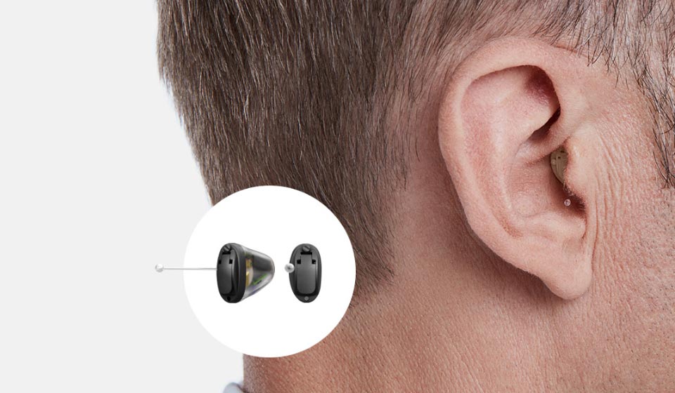 La imagen muestra el oído de un hombre con un audífono invisible dentro.