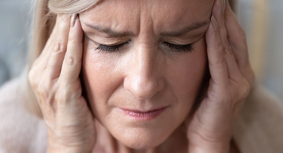 Image shows woman suffering from one of the consequences of untreated hearing loss