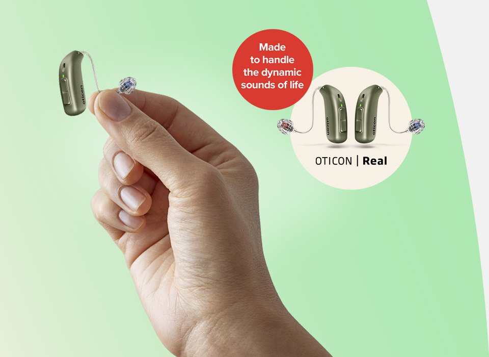 Dłoń trzymająca aparat słuchowy Oticon Real, który możesz teraz wypróbować.
