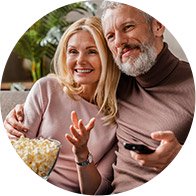 Image shows couple on sofa with popcorn and remote control in their hands