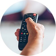 Image shows hand holding remote control