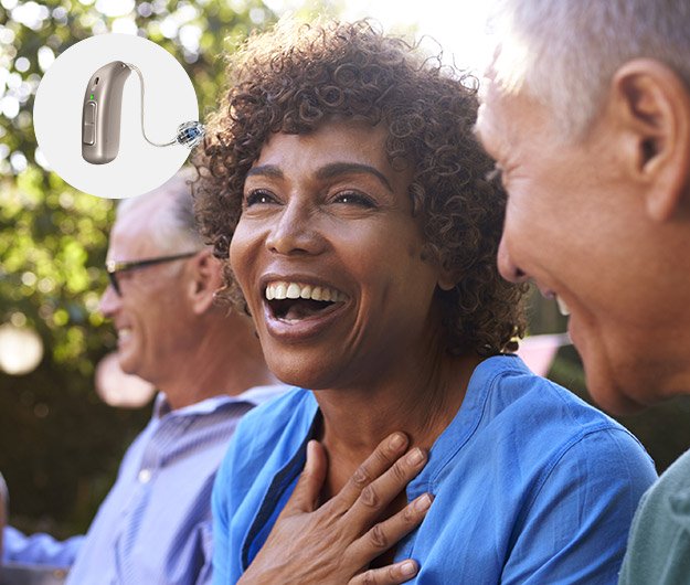 L'image montre une dame heureuse avec des appareils auditifs Audika Full