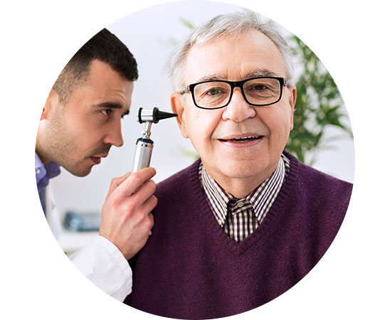Billedet viser en hørespecialist, der undersøger øret på en mand, hvis høretab er forårsaget af aldring