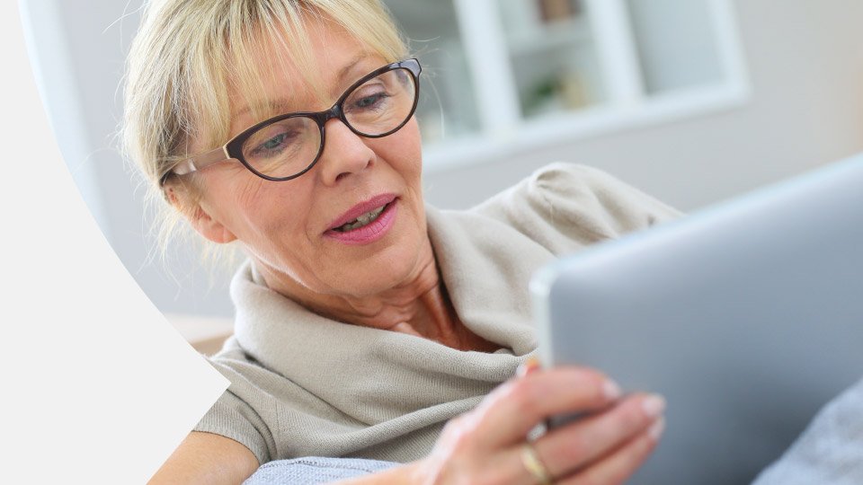 Bild zeigt eine lächelnde Frau, die auf ein Tablet schaut.