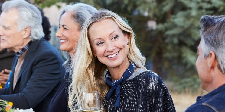 Image shows woman drinking at a table outdoors