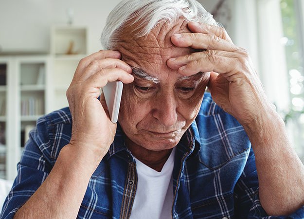 L’image montre un homme qui parle au téléphone tout en tenant sa tête