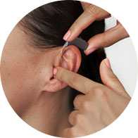 Afbeelding van audioloog die hoorapparaat in een oor plaatst